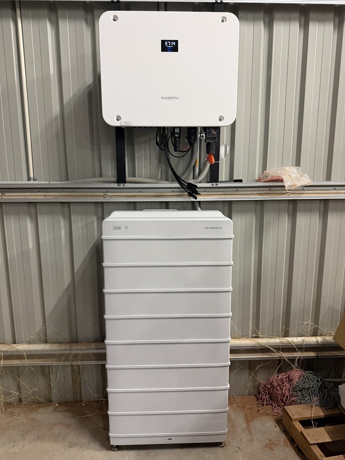 A Sungrow inverter and battery stack installed against a shed wall