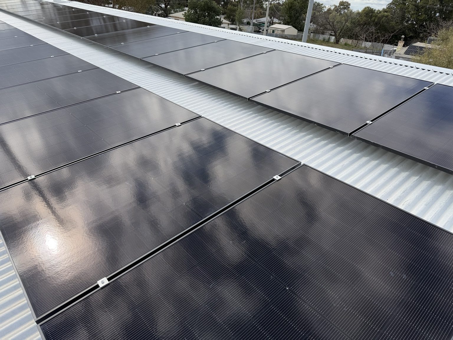 Close-up view of commercial rooftop solar panels reflecting a cloudy sky
