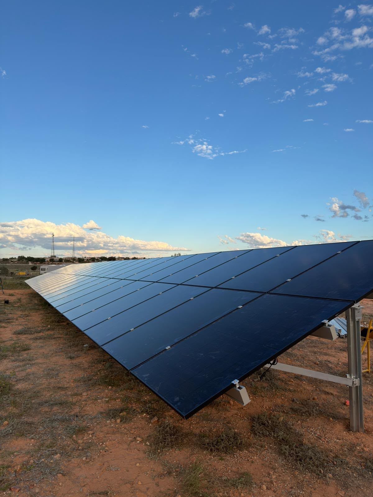A ground-mounted solar panel array viewed from below, showing the racking and panel underside