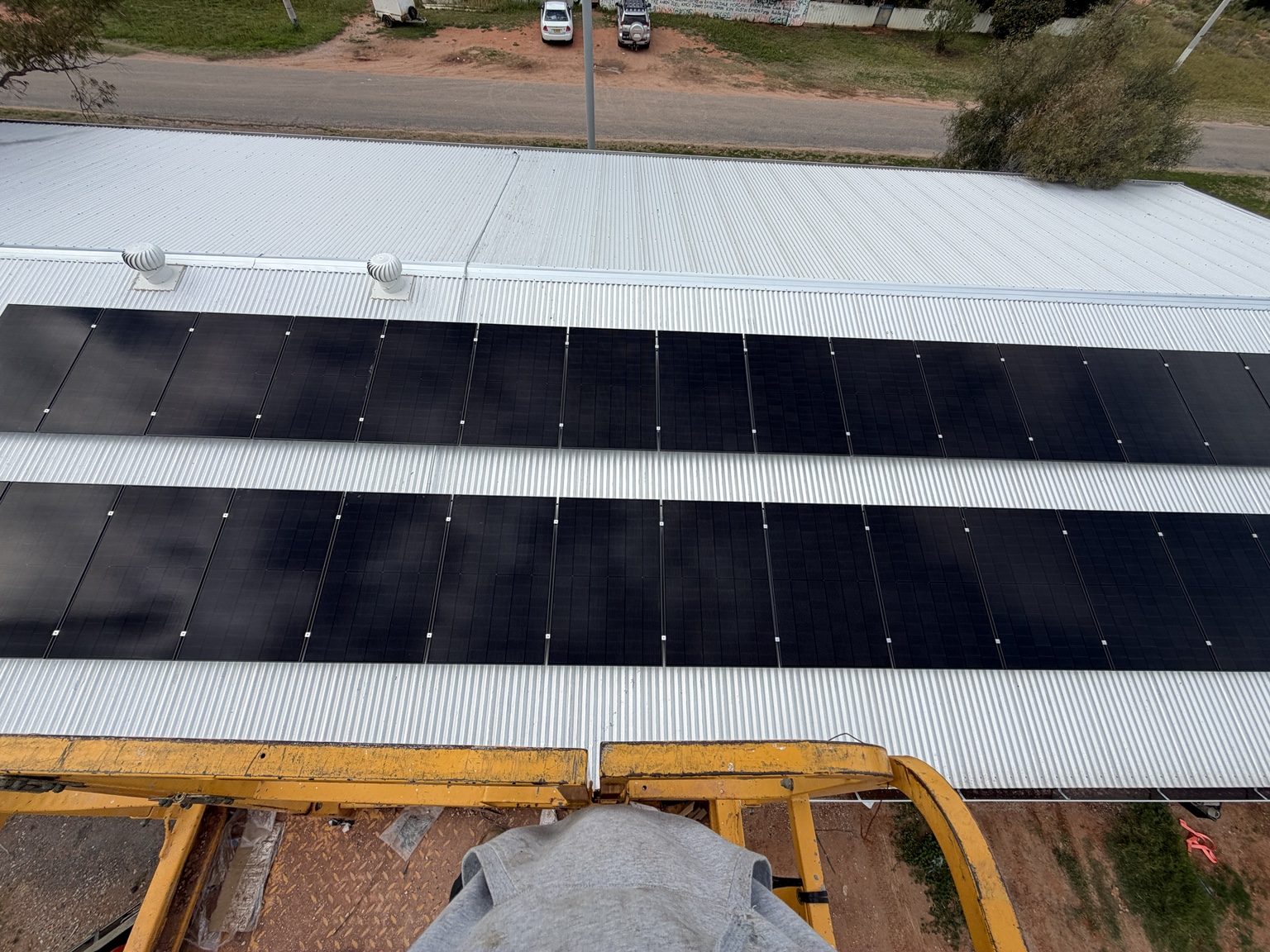 View from an elevated work platform over a partially completed commercial rooftop solar installation