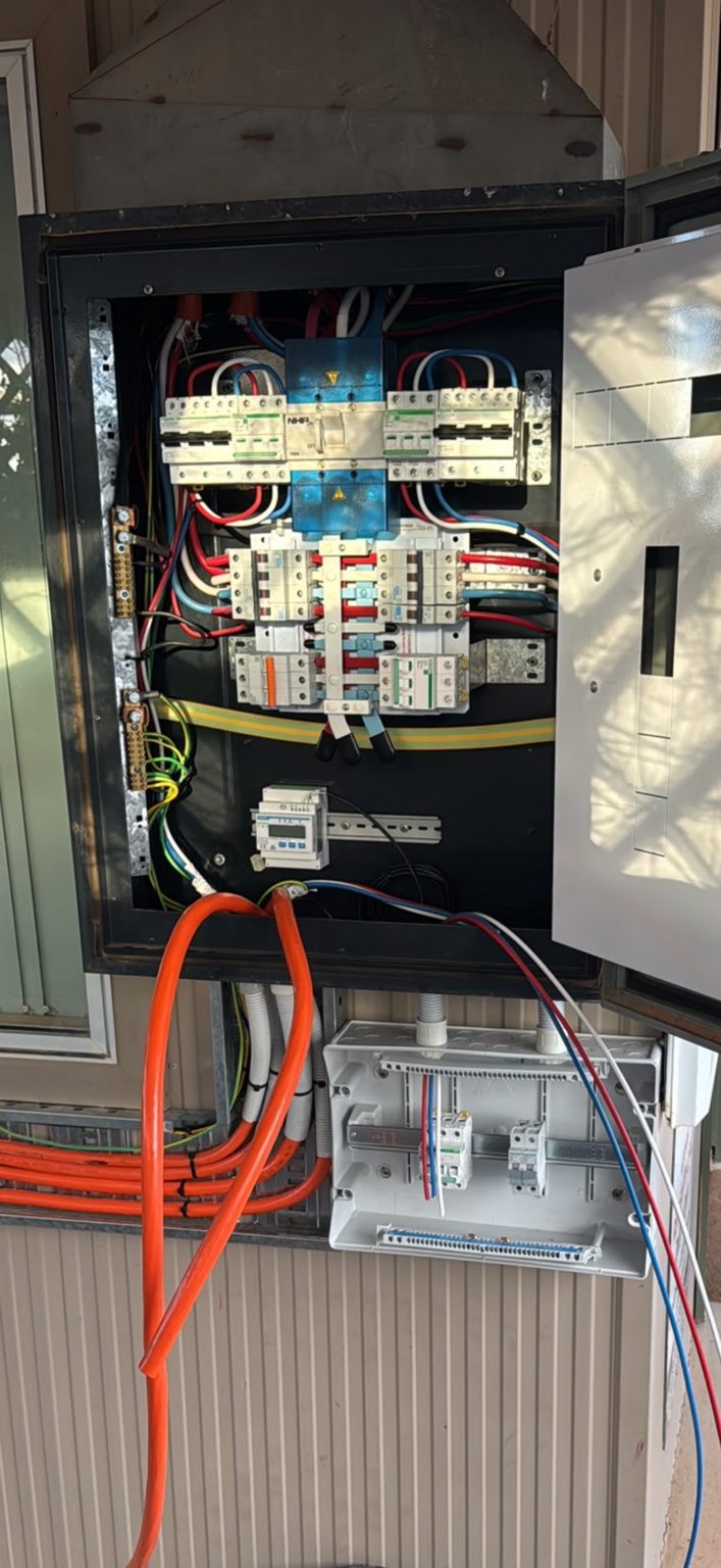 An open switchboard cabinet mid-installation, showing circuit breakers and wiring being connected
