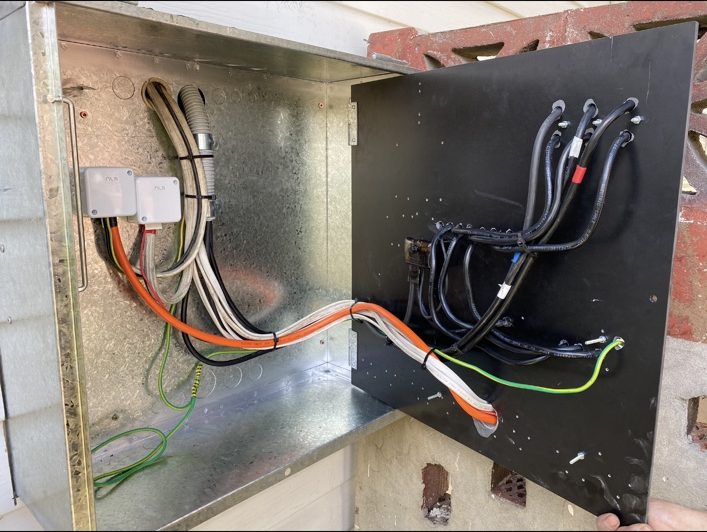 An open switchboard cabinet with wiring being connected during an installation